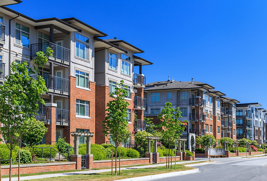 Modern apartment buildings with balconies and greenery under a clear blue sky