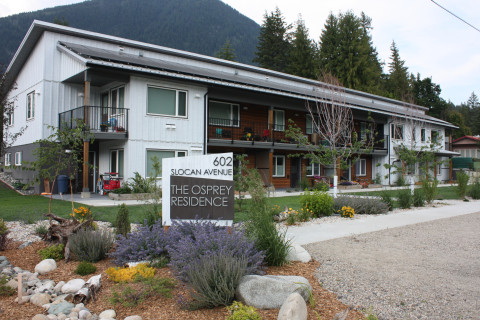 A two-storey building labelled ‘The Osprey Residence’ at 602 Slocan Ave, set against a backdrop of forested mountains.