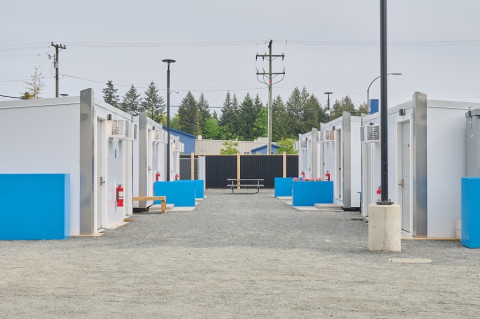 Row of modular housing units with blue accents and fire extinguishers outside.