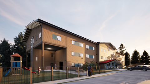 A modern multi-storey residential building with beige and brown exterior walls, shown during golden hour, featuring a playground on the left and a parked car on the right.