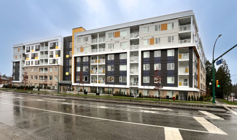 A six-storey building in white, orange, and navy blue, shown just after a rainfall.