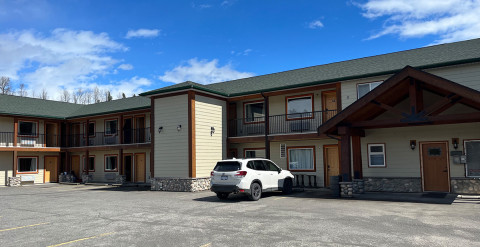 Forecourt surrounded by a two-storey apartment building with lodge-style architectural features.