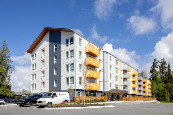 A long four-storey white and grey building with yellow balconies.