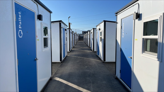 Outdoor hallway with rows of living quarters on both sides, each featuring bright blue doors.