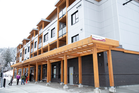 Exterior view of a white and black four-storey apartment building with a wood lattice structure over the entrance.