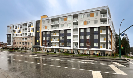 A six-storey building in white, orange, and navy blue, shown just after a rainfall.