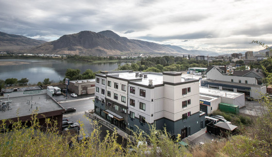 Four-storey apartment building in front of a lake and a mountain.