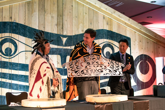 Special event attendee presenting an Indigenous art piece to B.C. Premier David Eby.