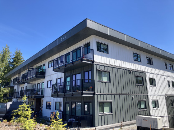 Angled view of a three-storey building with deep grey and white exterior walls.