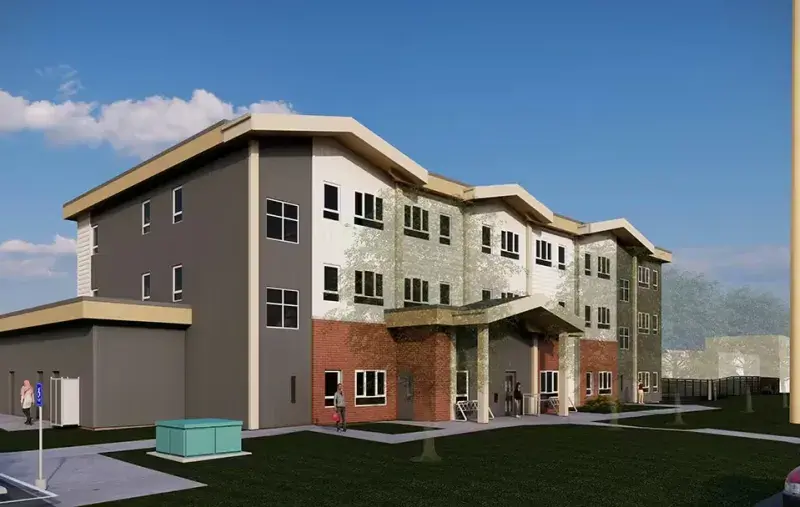 Architectural rendering of a four-storey residential building with a mix of grey, white, and brick façades, a covered main entrance, landscaped lawn, and people entering the building under a clear blue sky.