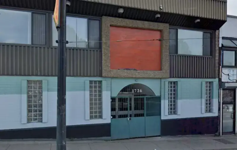 Street view of blue, white, brown and orange building. Two-storey with store front double doors.